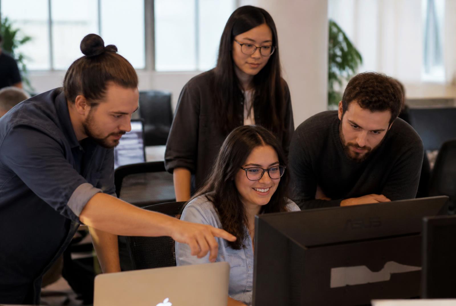 Software engineers reviewing work together on a monitor in a bright office